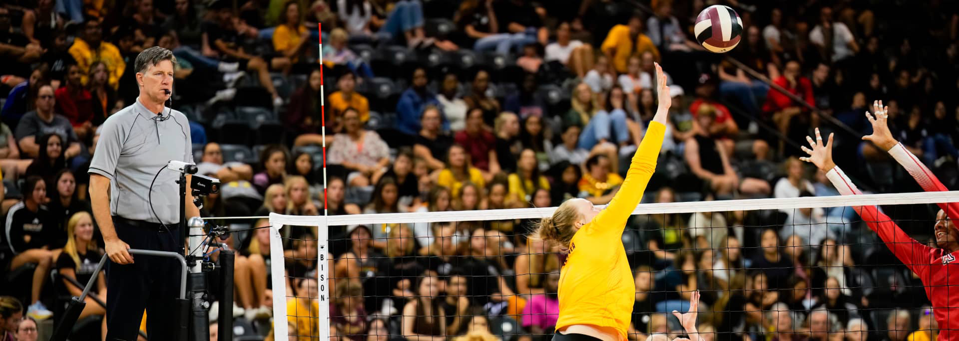 Sun Devil Volleyball player spiking the ball over the net against opponent