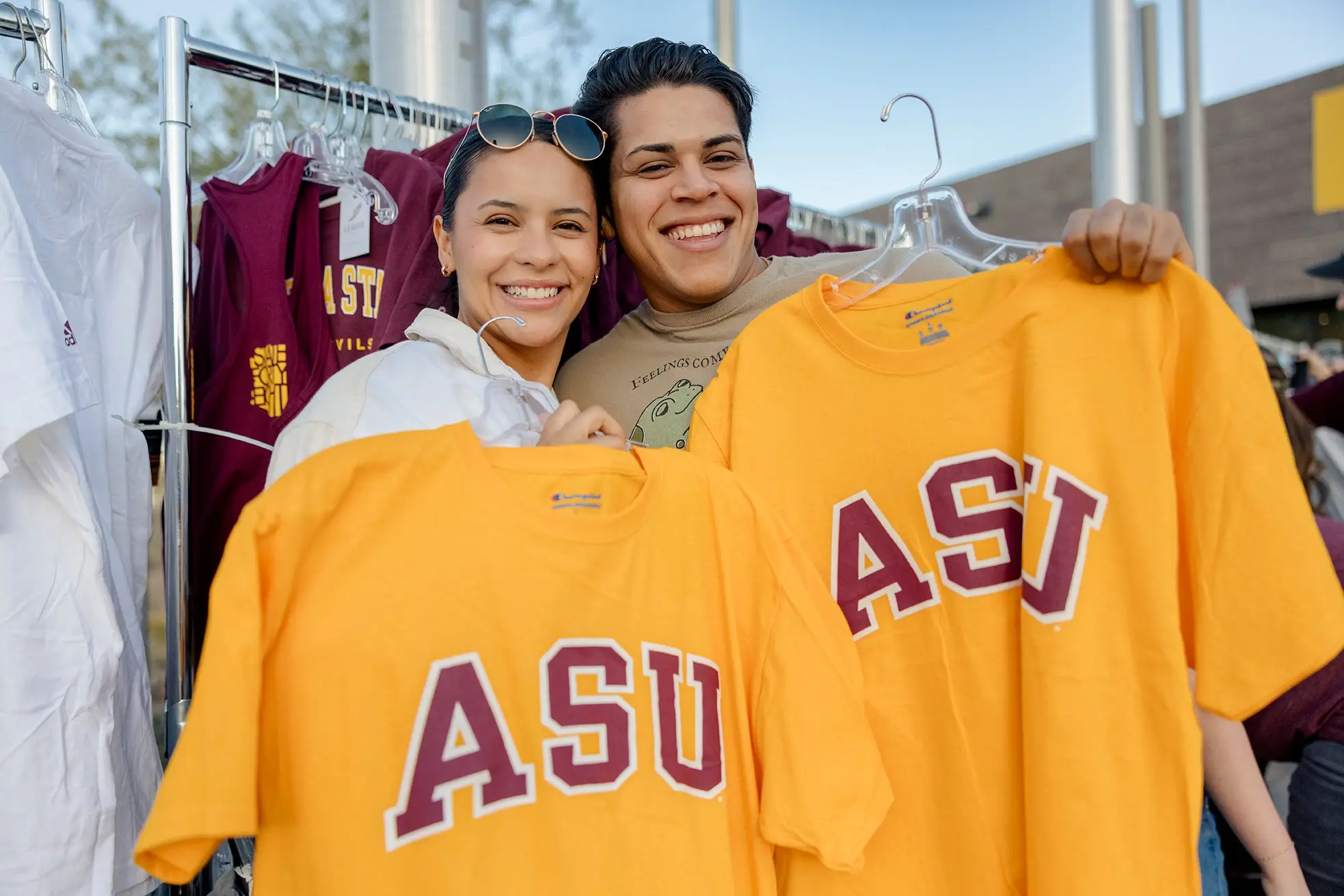 Couple holding asu branded shirts