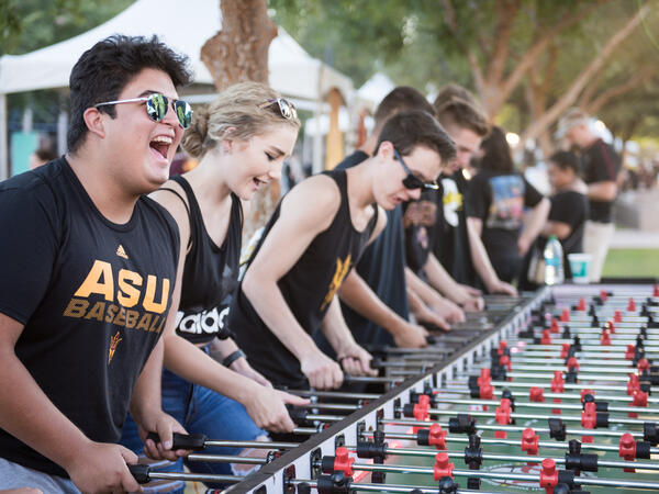 A group of ASU students play on a foosball table.