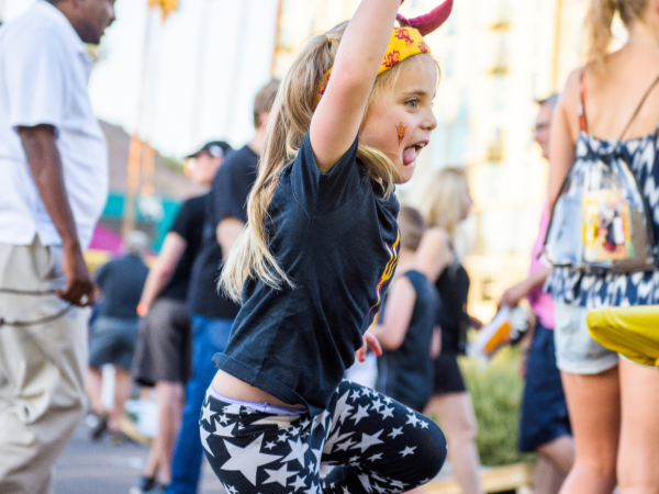 Young girl in ASU Sun Devil headband jumps with excitement