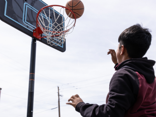 Child shooting basketball into hoop at Sun Devil Camp